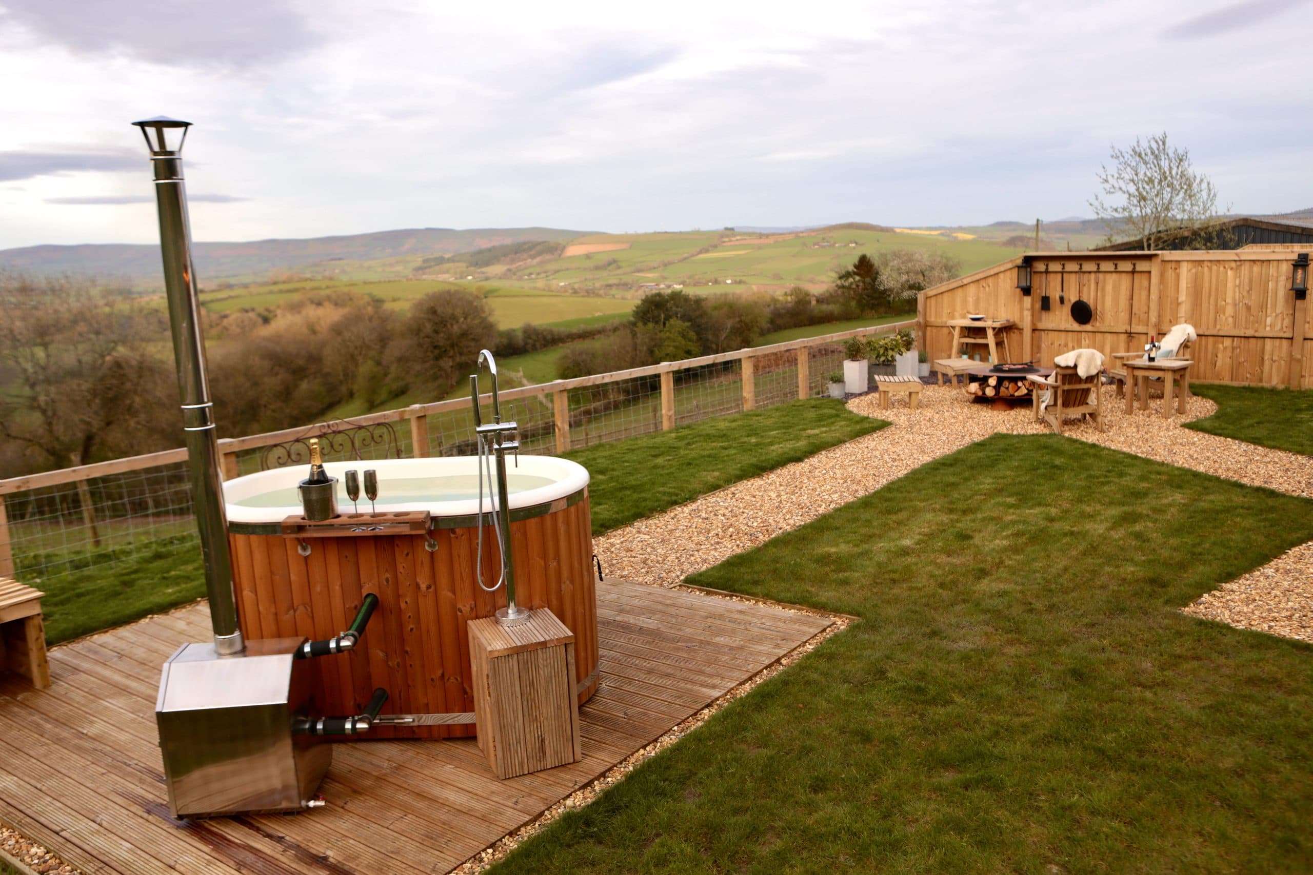 Oak Hut's hot tub deck with fire pit seating area and countryside views